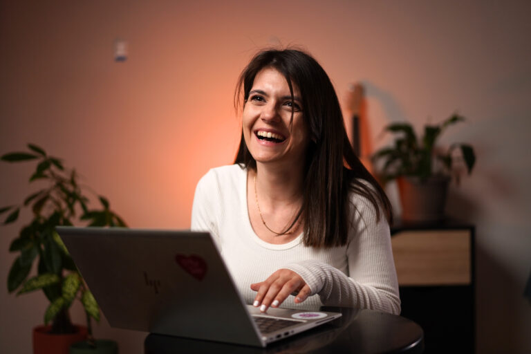 Marija Jovanović se smeje ispred laptopa u toploj večernjoj svetlosti